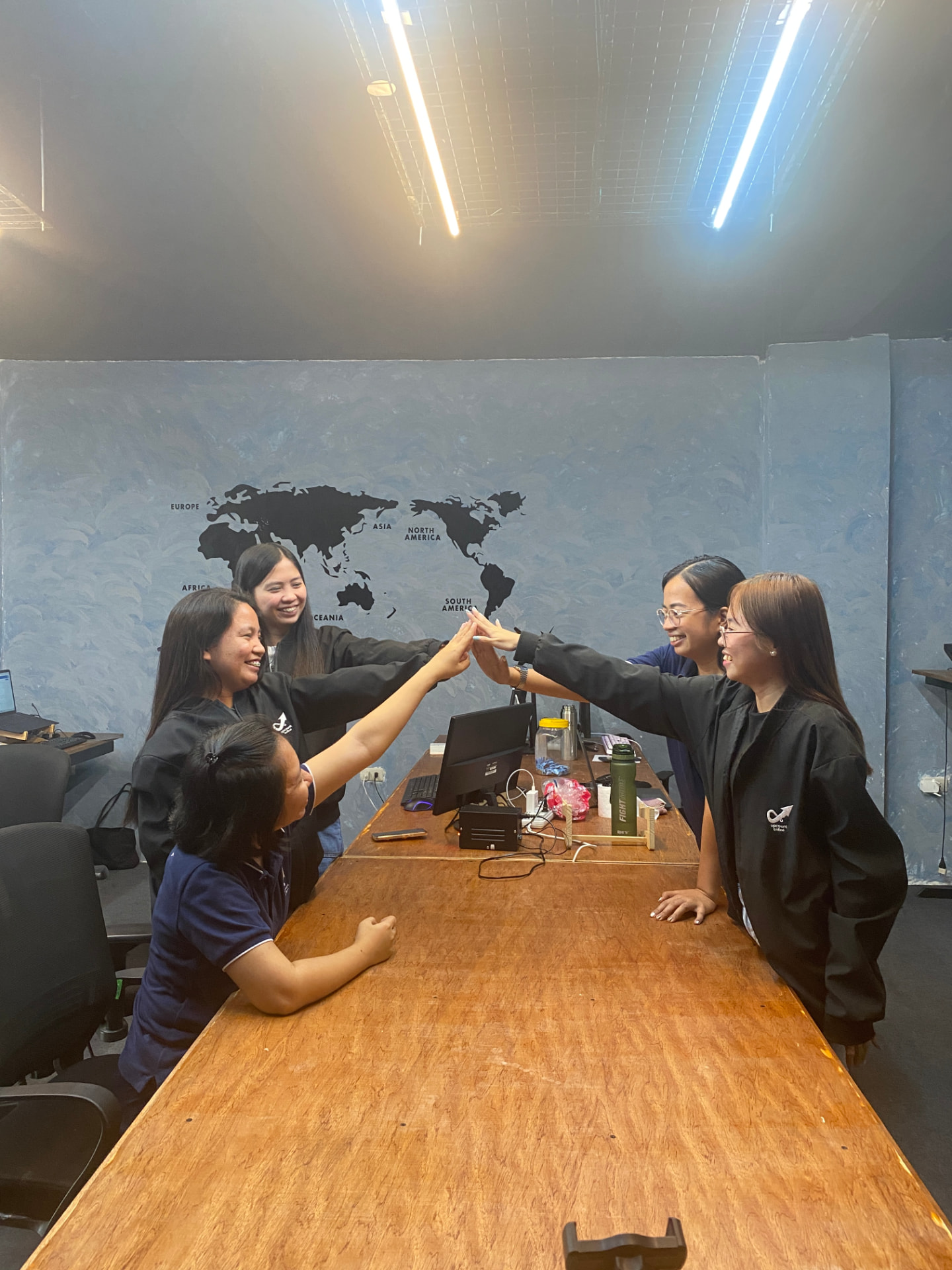 Upcount Online team celebrating with a high five around the office table