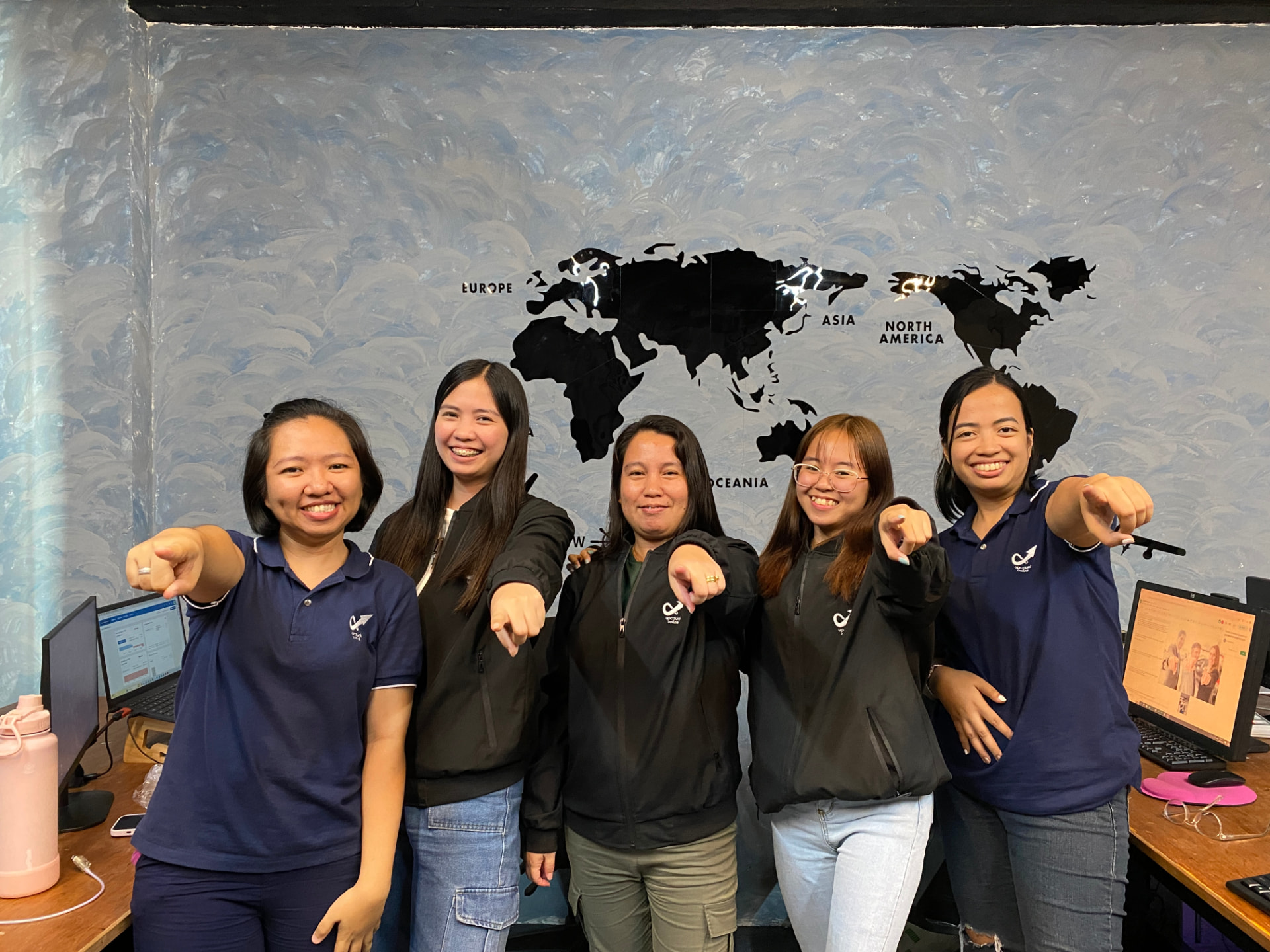 The Upcount Online team together in front of the office world map